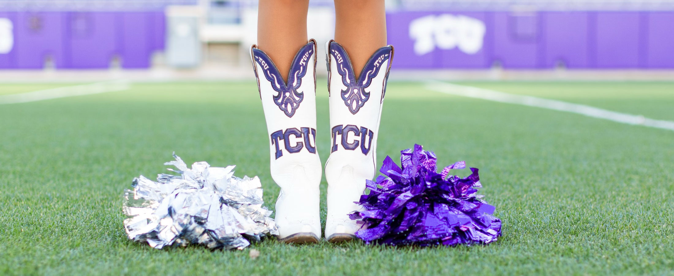 Las piernas de una corista de la TCU con sus botas posando para mostrar sus botas TCU personalizadas blancas y moradas.